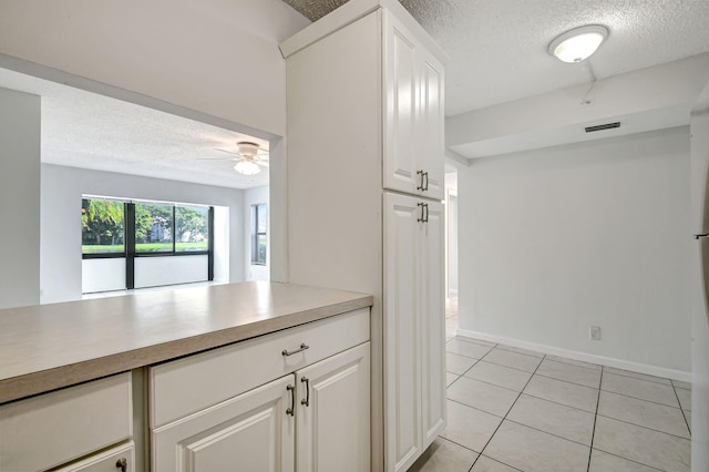 kitchen featuring white cabinetry, ceiling fan, a textured ceiling, and light tile patterned floors