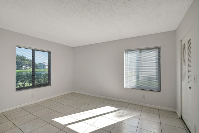 tiled empty room featuring a textured ceiling