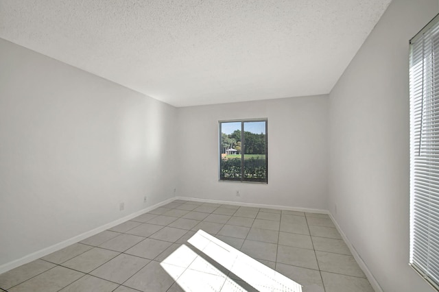 spare room with a textured ceiling and light tile patterned floors