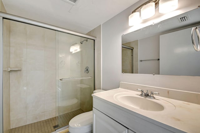 bathroom featuring toilet, a shower with shower door, and vanity