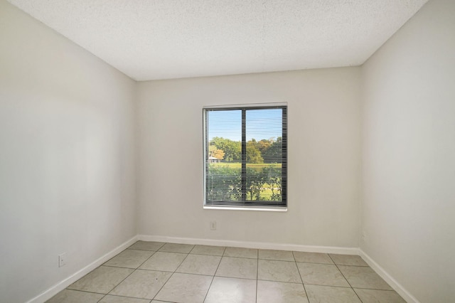 tiled empty room with a textured ceiling