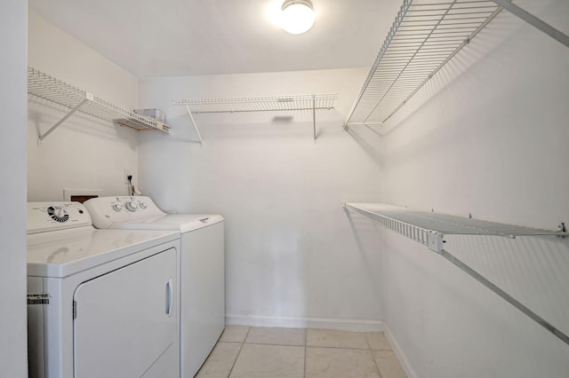 clothes washing area with washing machine and dryer and light tile patterned floors