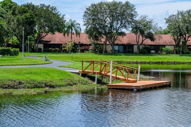 view of dock with a lawn and a water view