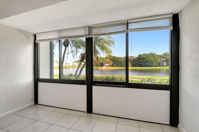 tiled empty room with a textured ceiling and a water view