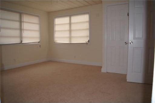 unfurnished bedroom featuring light carpet and wood ceiling