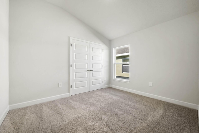 unfurnished bedroom with a closet, carpet floors, and vaulted ceiling