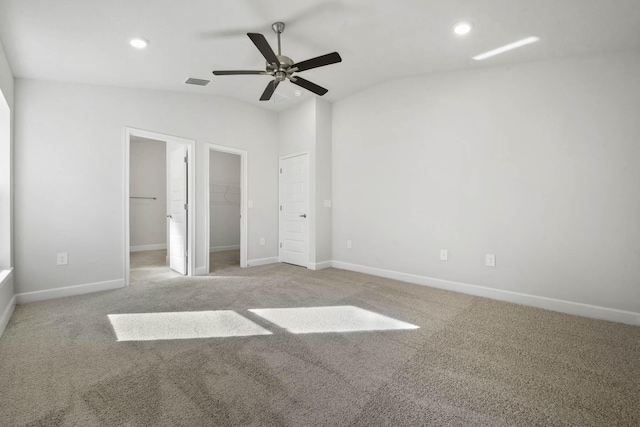 unfurnished bedroom featuring a walk in closet, ceiling fan, a closet, and light carpet