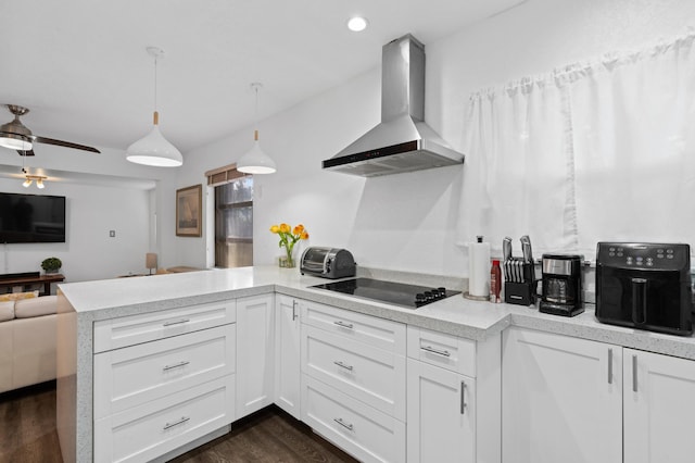 kitchen with white cabinetry, wall chimney exhaust hood, kitchen peninsula, and hanging light fixtures