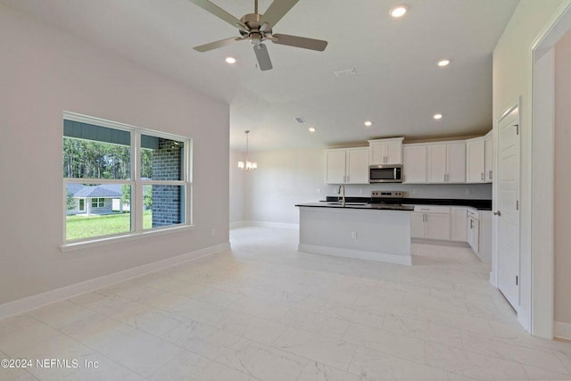 kitchen with a kitchen island with sink, white cabinets, ceiling fan with notable chandelier, sink, and appliances with stainless steel finishes