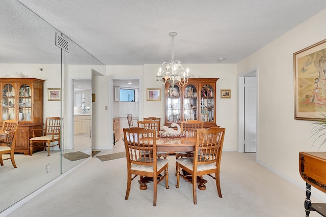 dining area featuring a textured ceiling, light colored carpet, and an inviting chandelier