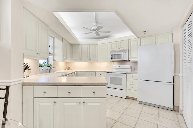 kitchen featuring white cabinetry, a raised ceiling, white appliances, and sink