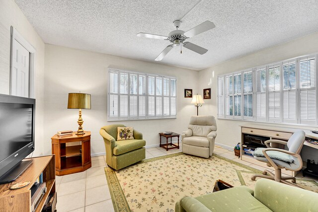 living area with ceiling fan, light tile patterned flooring, and a textured ceiling