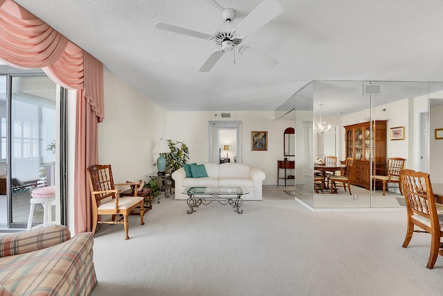 carpeted living room featuring a textured ceiling and ceiling fan with notable chandelier