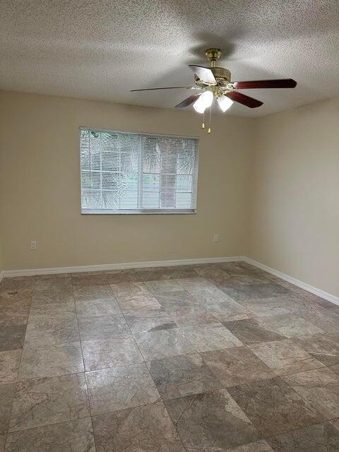 unfurnished room with ceiling fan and a textured ceiling