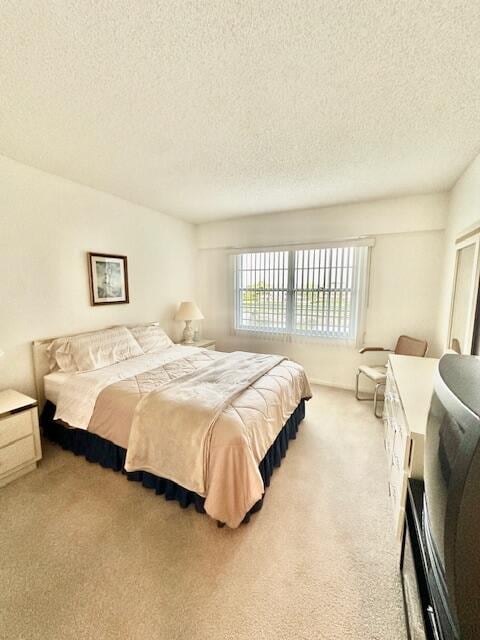 bedroom featuring a textured ceiling and light colored carpet