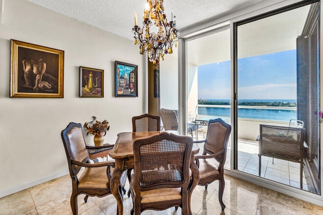 dining space with a water view, light tile patterned flooring, baseboards, a textured ceiling, and a notable chandelier