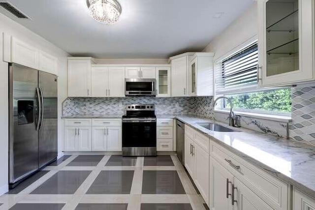 kitchen with stainless steel appliances, tasteful backsplash, sink, and white cabinets