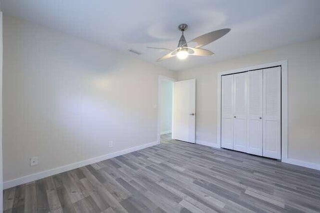 unfurnished bedroom featuring a closet, hardwood / wood-style floors, and ceiling fan