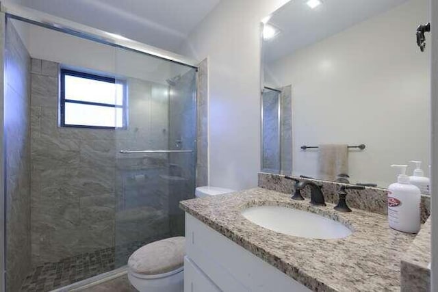 bathroom with toilet, a shower with shower door, and vanity