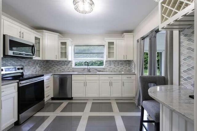 kitchen featuring appliances with stainless steel finishes, a healthy amount of sunlight, sink, and tasteful backsplash