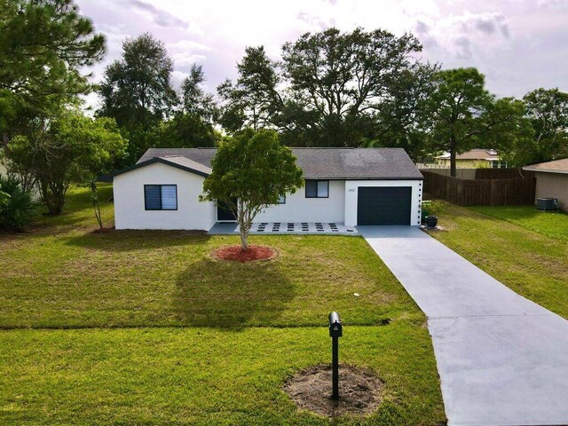 single story home featuring concrete driveway, an attached garage, fence, a front lawn, and stucco siding