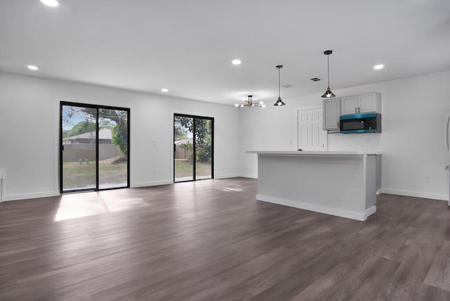 kitchen featuring dark wood-type flooring, open floor plan, light countertops, gray cabinets, and decorative light fixtures