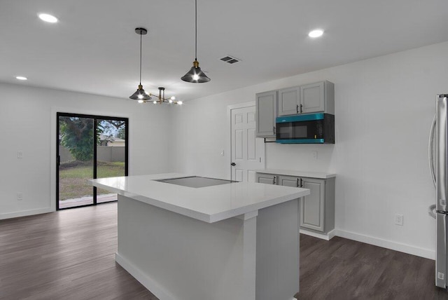 kitchen with black electric stovetop, gray cabinets, light countertops, visible vents, and a kitchen island