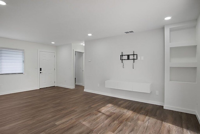 empty room featuring dark wood-style floors, visible vents, baseboards, and recessed lighting