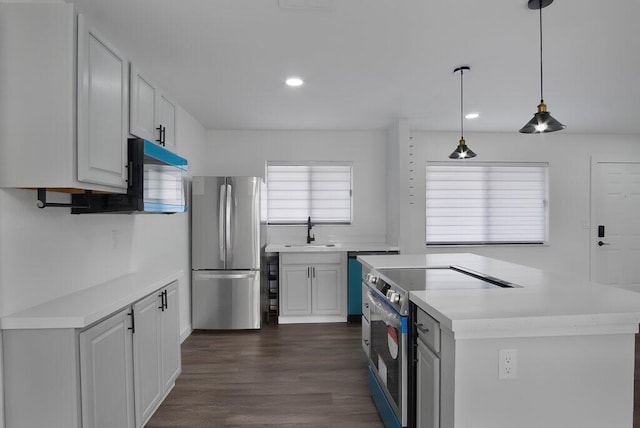 kitchen with stainless steel appliances, a sink, white cabinetry, light countertops, and decorative light fixtures