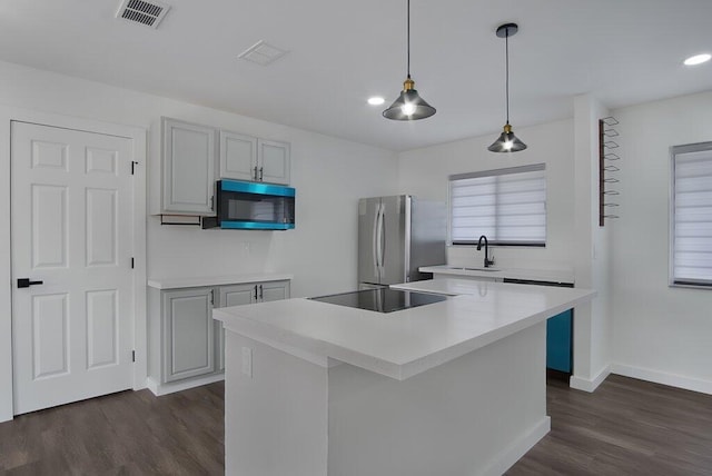 kitchen with visible vents, light countertops, hanging light fixtures, freestanding refrigerator, and a center island