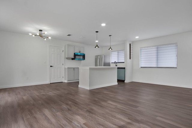 kitchen with a center island, stainless steel appliances, light countertops, hanging light fixtures, and gray cabinetry