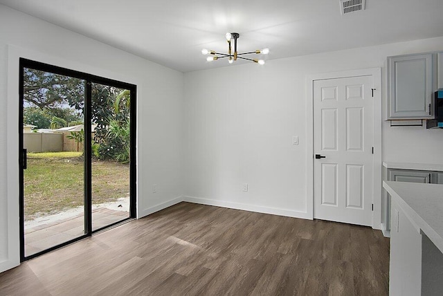 unfurnished dining area featuring an inviting chandelier, plenty of natural light, visible vents, and dark wood-type flooring