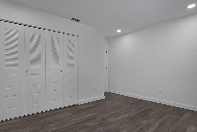 unfurnished bedroom featuring dark wood-style floors, baseboards, visible vents, and a closet