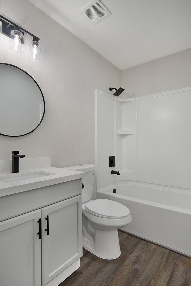 full bathroom with visible vents, toilet, vanity, shower / tub combination, and wood finished floors