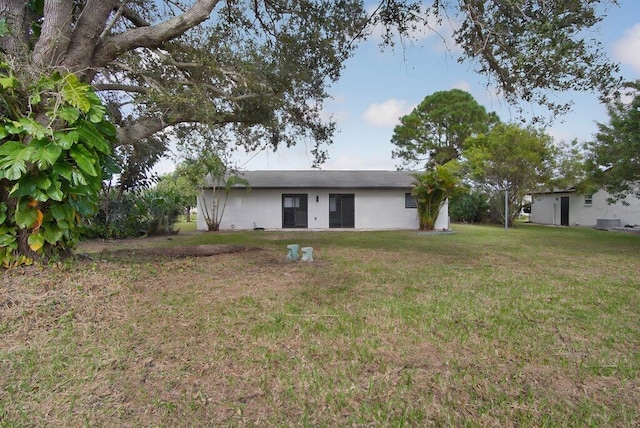 rear view of house featuring stucco siding and a yard