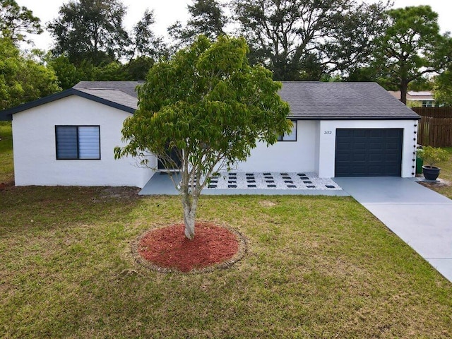 single story home with a garage, a front yard, concrete driveway, and stucco siding