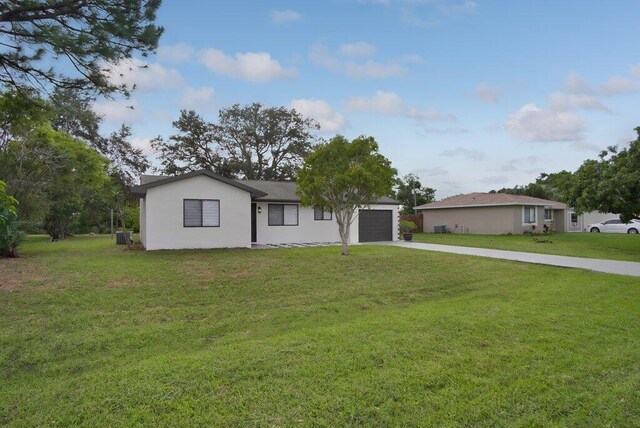 ranch-style home with an attached garage, stucco siding, concrete driveway, and a front yard