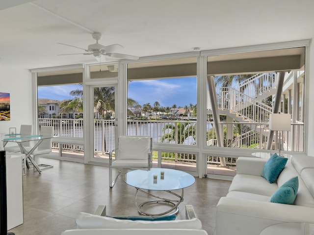 sunroom with ceiling fan, a water view, and plenty of natural light