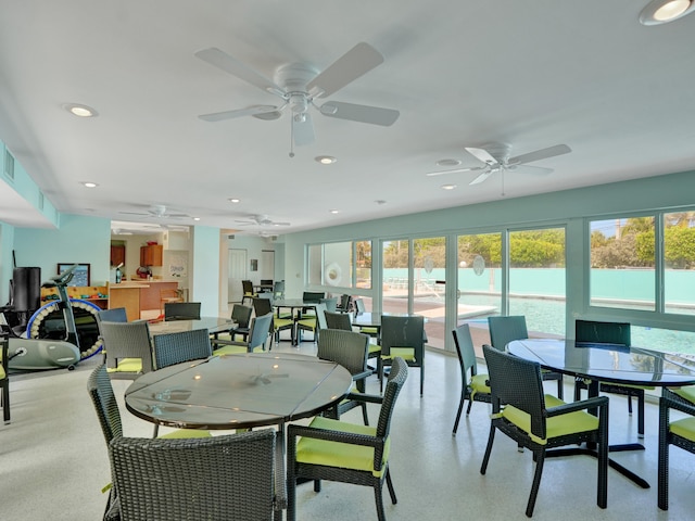 dining area with a water view and ceiling fan