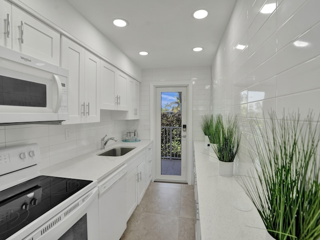 kitchen with white appliances, sink, white cabinets, light stone counters, and light tile patterned floors