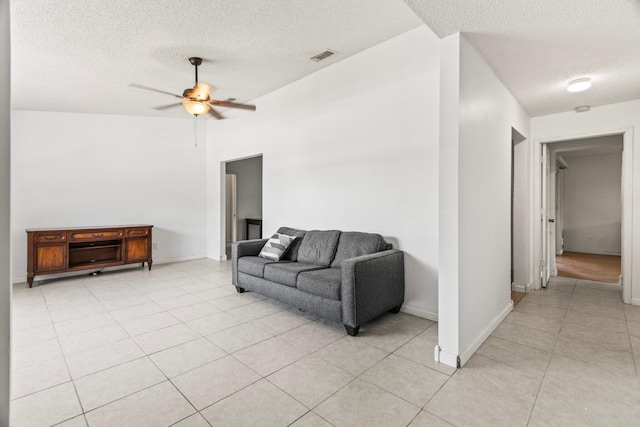 living room with a textured ceiling, light tile patterned flooring, vaulted ceiling, and ceiling fan