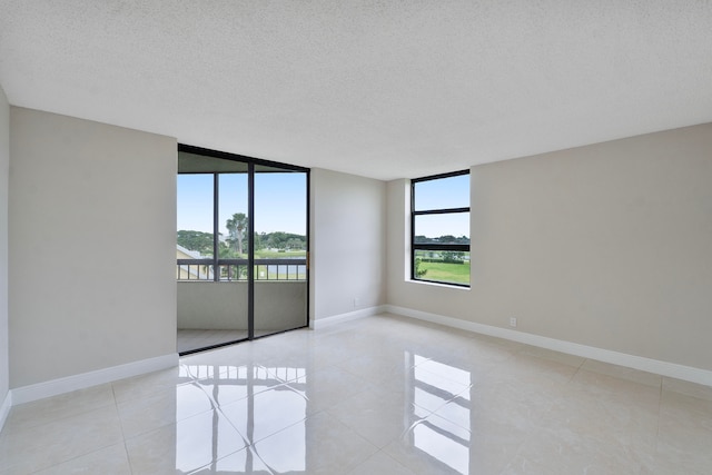 tiled spare room with a textured ceiling and floor to ceiling windows