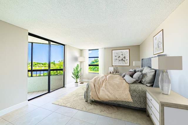 bedroom featuring a textured ceiling, light tile patterned flooring, expansive windows, and access to exterior