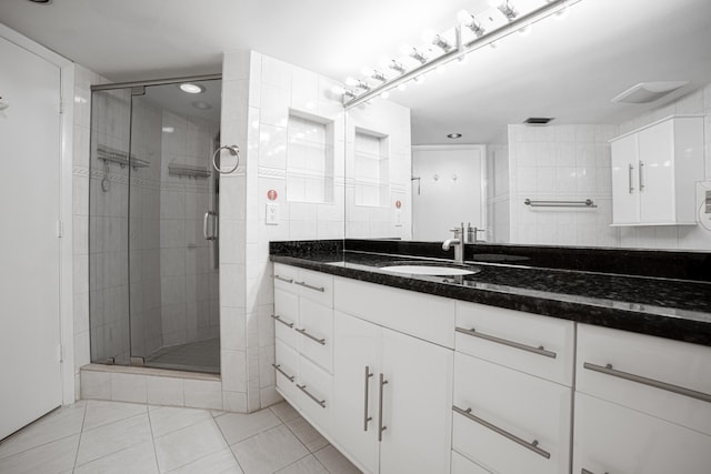 bathroom with vanity, tile patterned floors, a shower with door, and tile walls