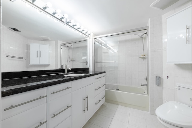 full bathroom with toilet, tile walls, tiled shower / bath, vanity, and tile patterned flooring