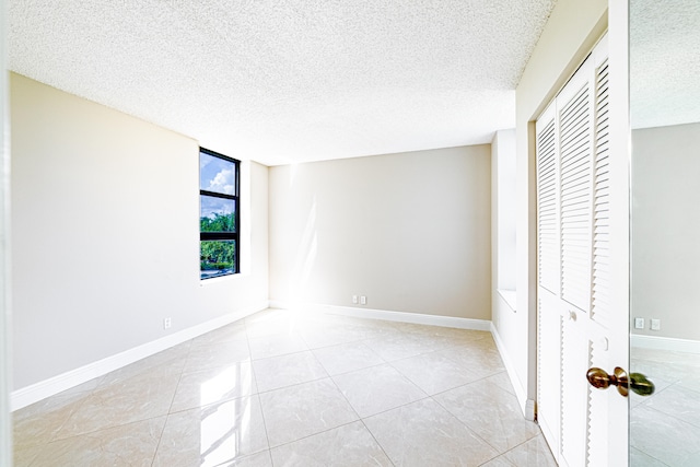 unfurnished bedroom with a textured ceiling, a closet, and light tile patterned floors