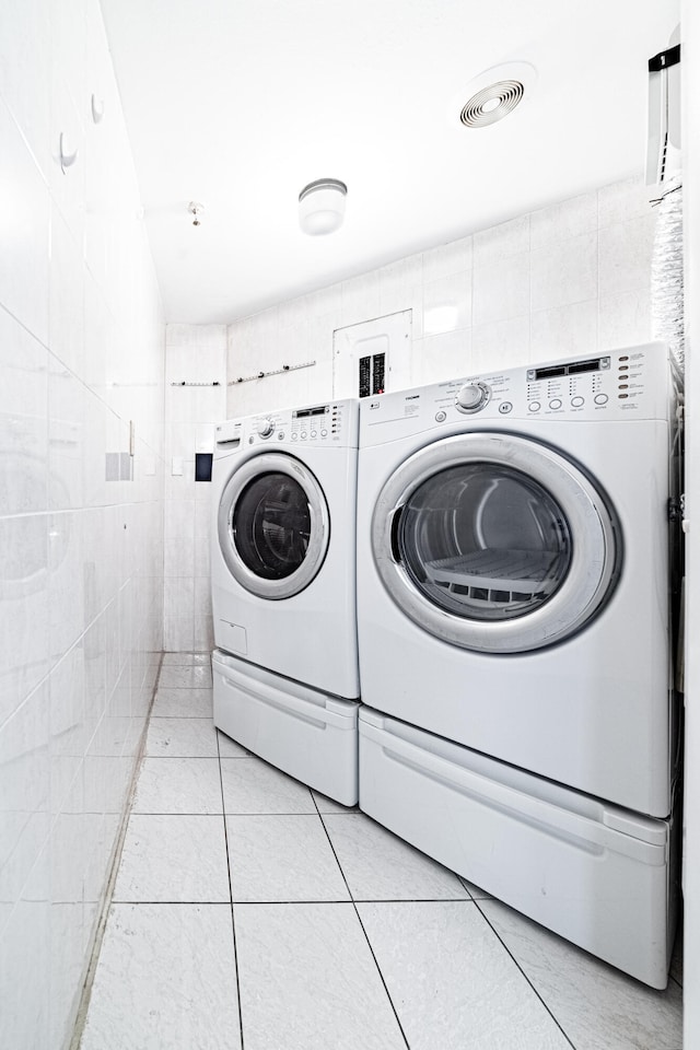 washroom featuring tile walls, light tile patterned flooring, and independent washer and dryer