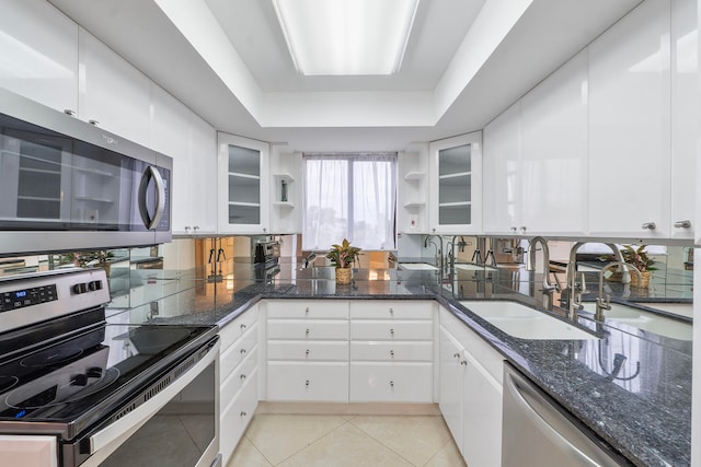 kitchen with light tile patterned floors, appliances with stainless steel finishes, white cabinetry, a tray ceiling, and sink