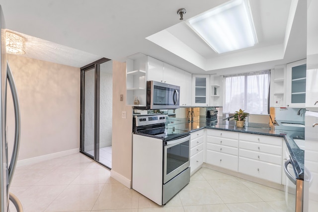 kitchen featuring stainless steel appliances, light tile patterned flooring, a raised ceiling, and white cabinets