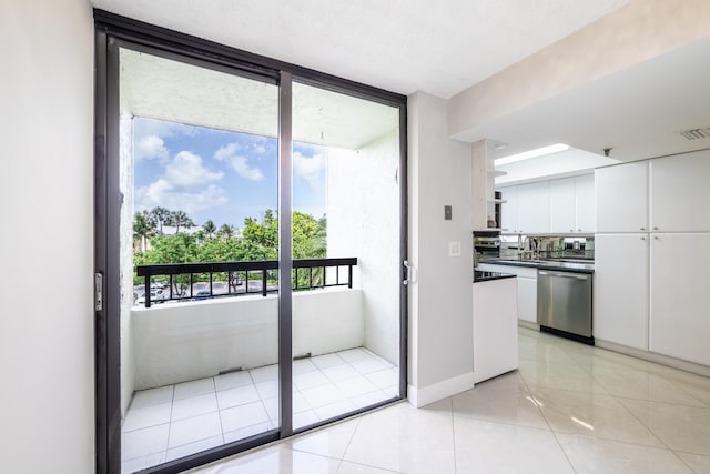 kitchen featuring stainless steel dishwasher, white cabinetry, and light tile patterned floors